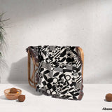 Black and white classical checker board pattern woven blanket throw on a wooden chair against a light background.