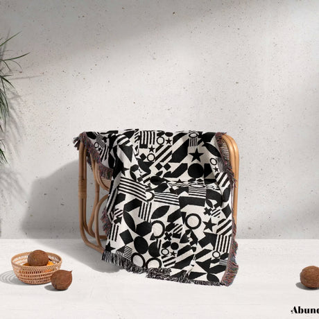 Black and white classical checker board pattern woven blanket throw on a wooden chair against a light background.