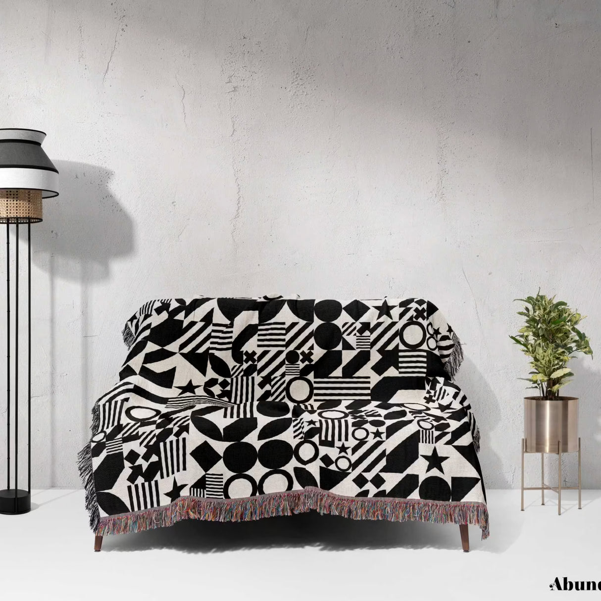 Sofa with a black and white classical checker board pattern woven blanket throw against a white wall.
