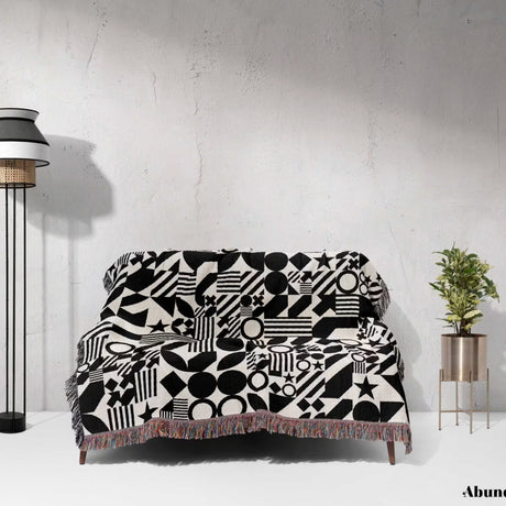 Sofa with a black and white classical checker board pattern woven blanket throw against a white wall.