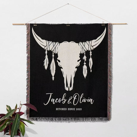 Cow skull wedding 2nd anniversary gift woven throw blanket with white bull skull design and text, hanging on a wall as a cotton tapestry.