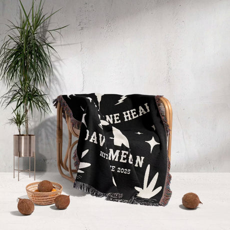 Cow skull and boots 2nd anniversary gift woven throw blanket with white text and graphics draped over a chair in a room with a plant and decorative items.