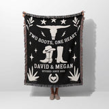 Cow skull and boots 2nd anniversary gift woven throw blanket with white text and graphics, including boots and a skull, held by a person on a white background.