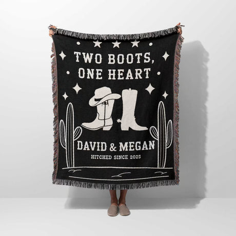 Cowboy boots wedding 2nd anniversary gift woven throw blanket with white text and graphics, featuring cowboy boots and cacti, held by a person.