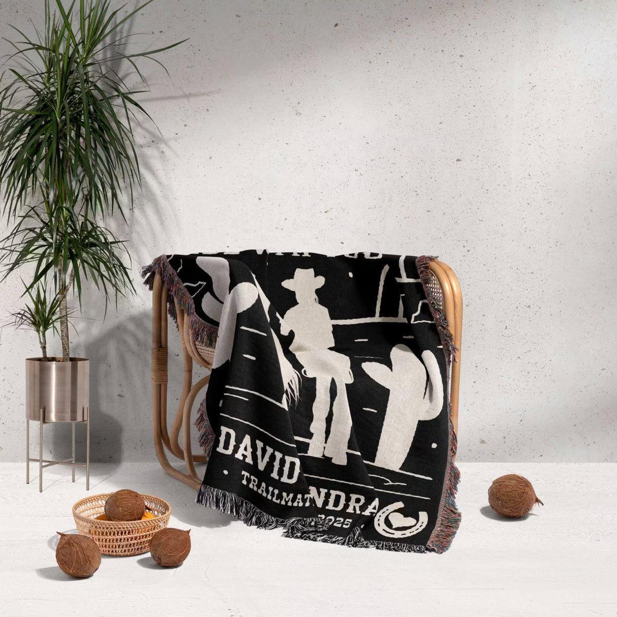 Cowboy and cowgirl 2nd anniversary gift woven throw blanket with white graphics and text draped over a chair, with a plant and decorative items in the background.