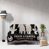 Cowboy and cowgirl 2nd anniversary gift woven throw blanket with western designs and personalized text on a couch against a white wall.