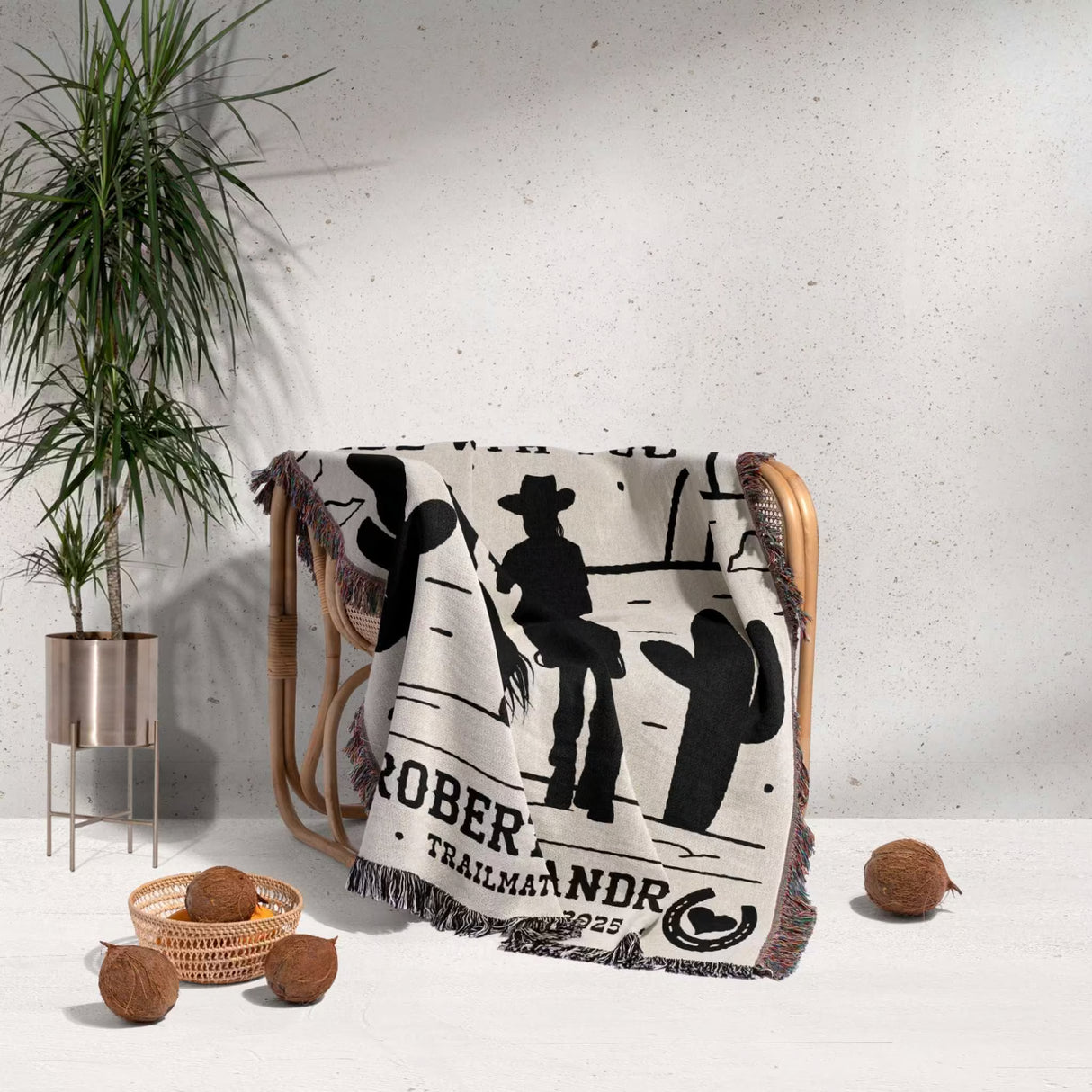 Cowboy and cowgirl cotton anniversary gift woven throw blanket with cowboy design on a chair next to a plant and decorative items.