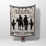 Cowboy and cowgirl cotton anniversary gift woven throw blanket held by a person with cowboy design and text on a white background