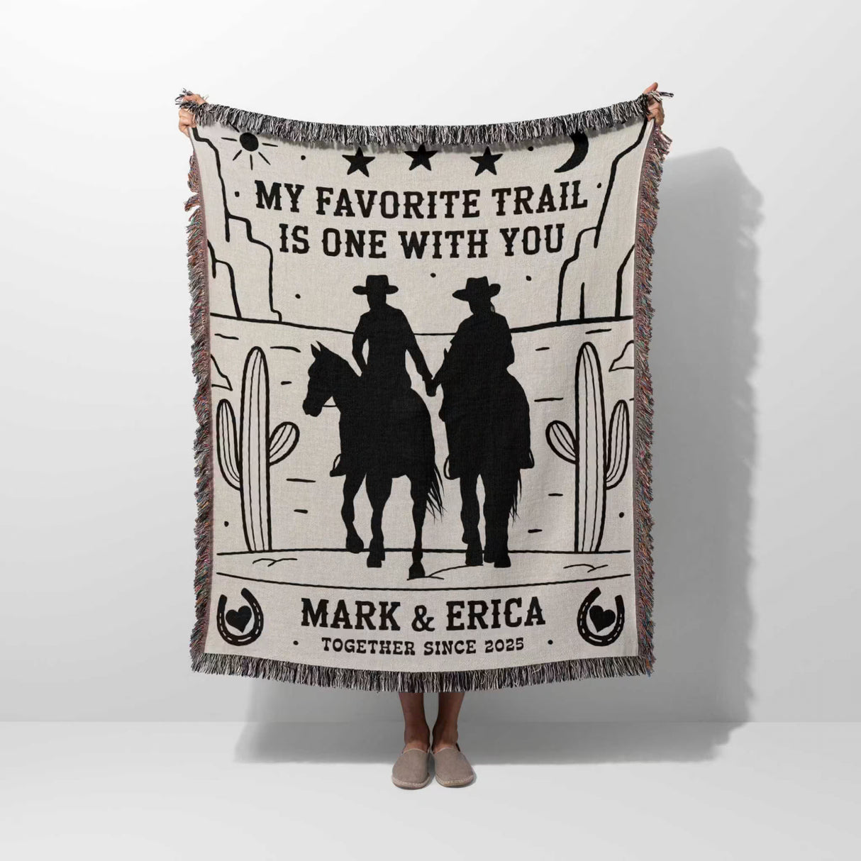Cowboy and cowgirl couple cotton anniversary gift woven throw blanket with cowboy design and text, held by a person on a white background
