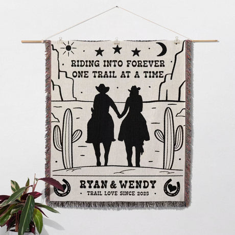 Cowboy and cowgirl western cotton anniversary gift woven throw blanket with cowboy design and text, hanging on a wall.