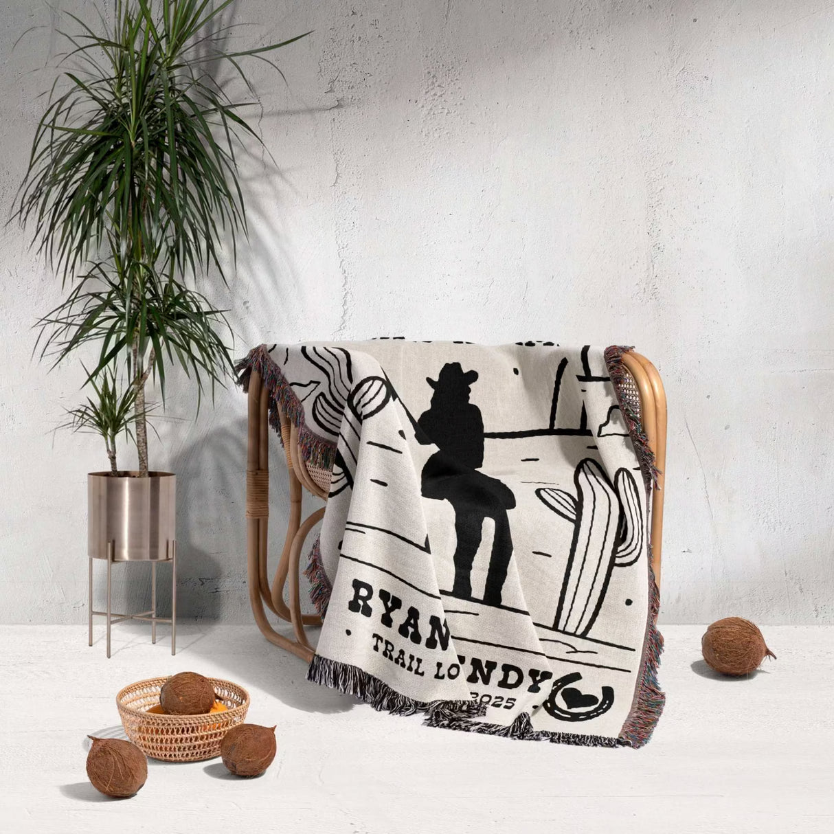 Cowboy and cowgirl western cotton anniversary gift woven throw blanket with a western design and text draped over a chair in a room with a plant and decorative items.