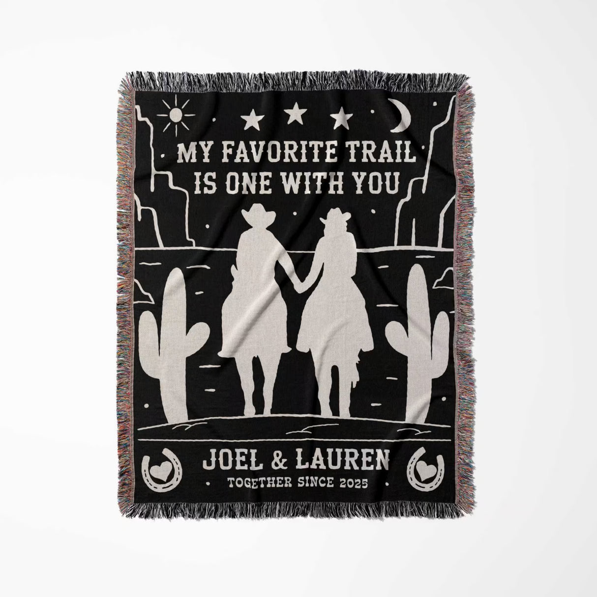 Cowboy and cowgirl on two horses 2nd anniversary gift woven throw blanket full view with desert scene design, couple holding hands, and personalized text on a black background.