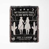 Cowboy and cowgirl on two horses 2nd anniversary gift woven throw blanket full view with desert scene design, couple holding hands, and personalized text on a black background.