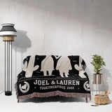 Cowboy and cowgirl on two horses 2nd anniversary gift woven throw blanket with 'Joel & Lauren Together Since 2023' text draped over a couch in a room setting.