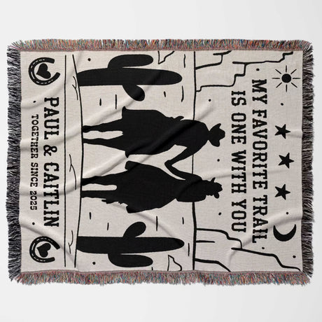 Cowboy and cowgirl on two horses cotton anniversary gift woven throw blanket flat lay with cowboy design and text on a white background