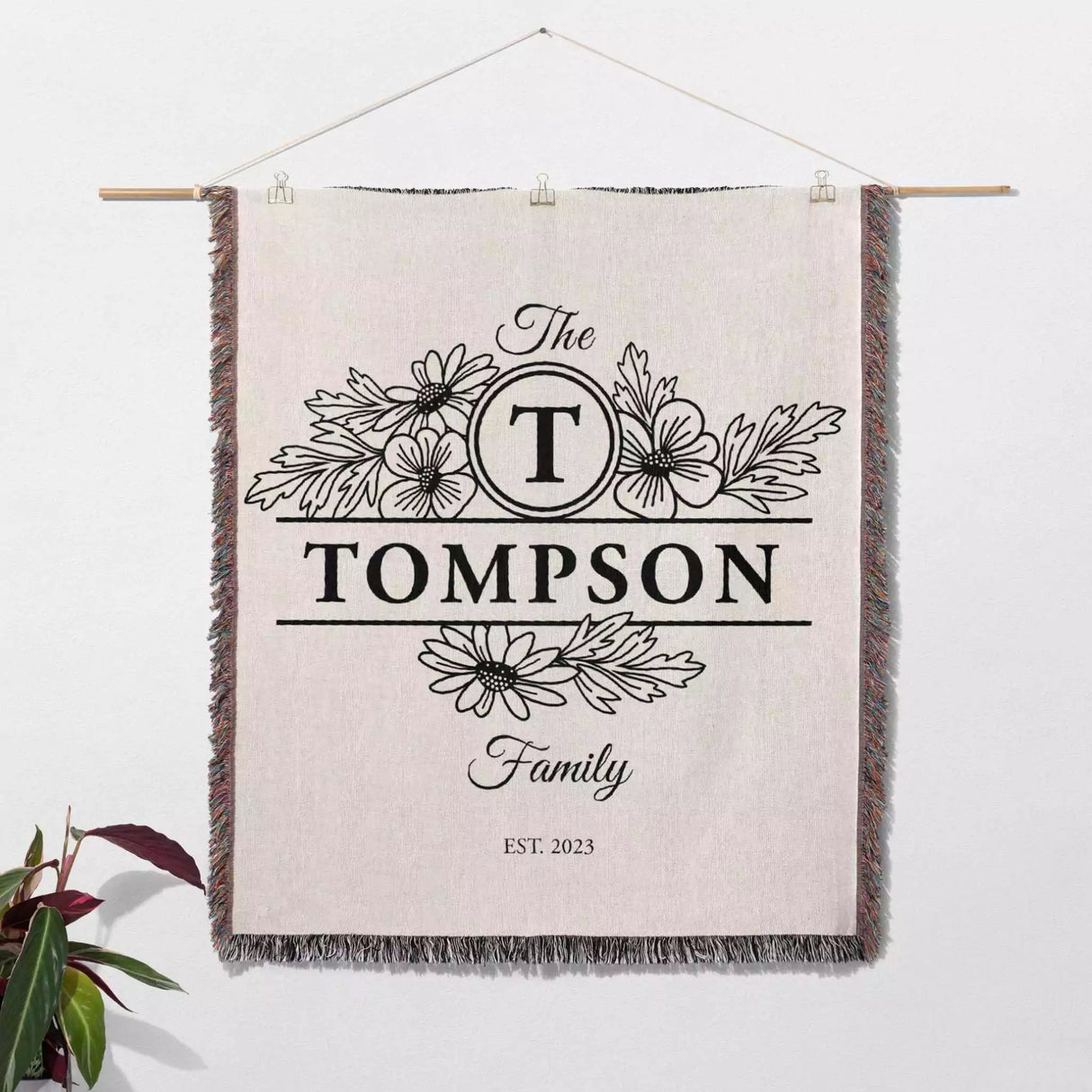 Custom family name blanket with 'The Tompson Family' design hanging on a white wall.