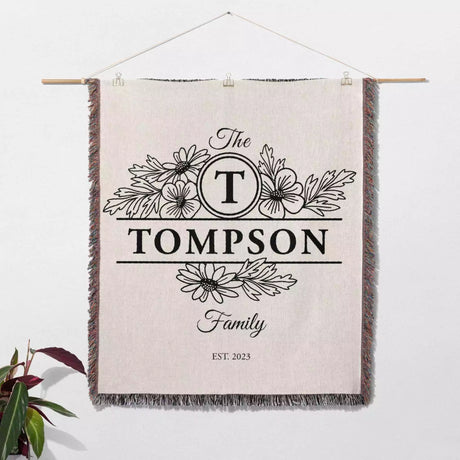 Custom family name blanket with 'The Tompson Family' design hanging on a white wall.