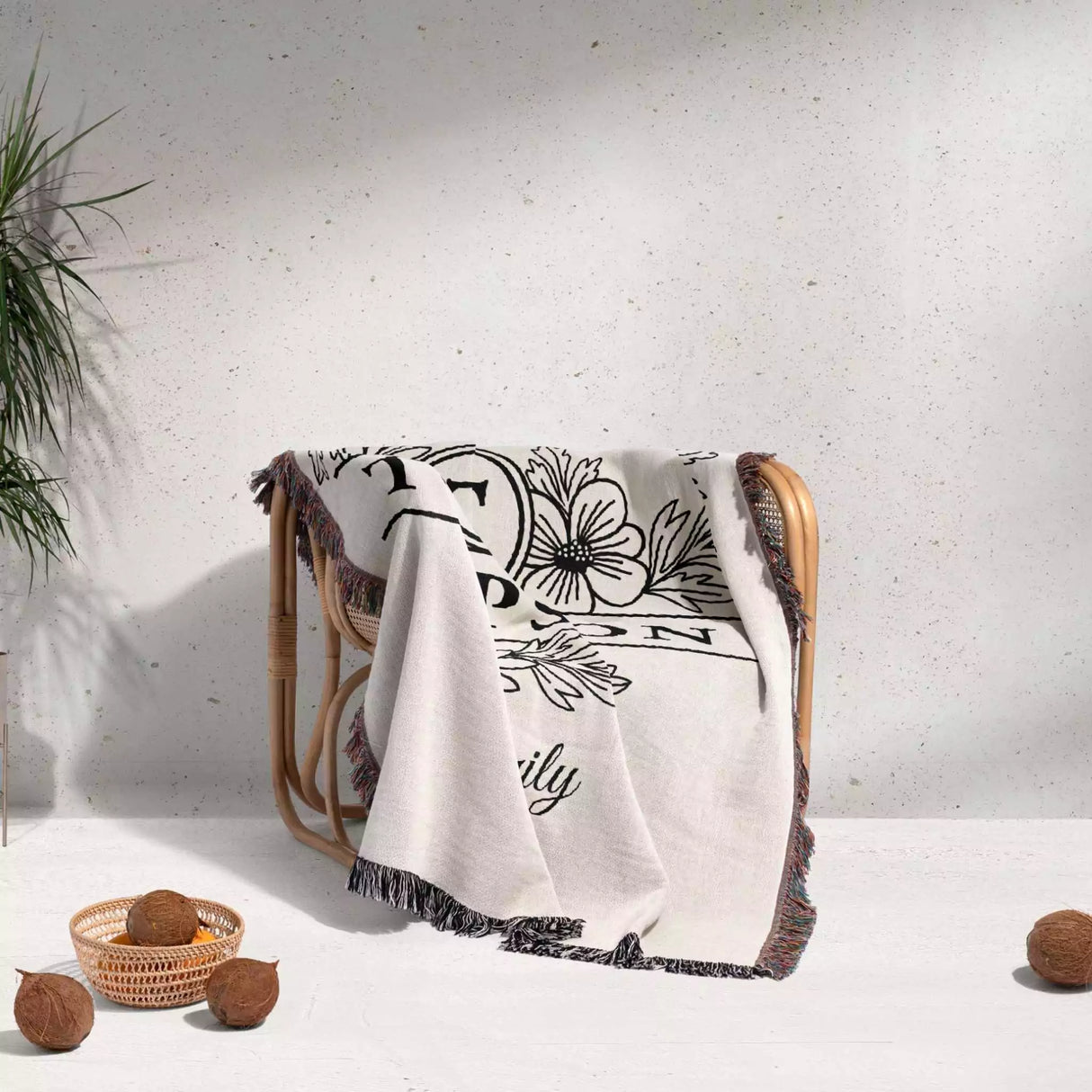 Custom family name blanket with floral design and text draped over a chair on a light background