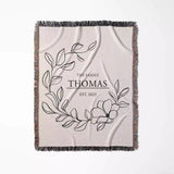 Custom family name cotton throw blanket with floral design and text flat lay on a white background