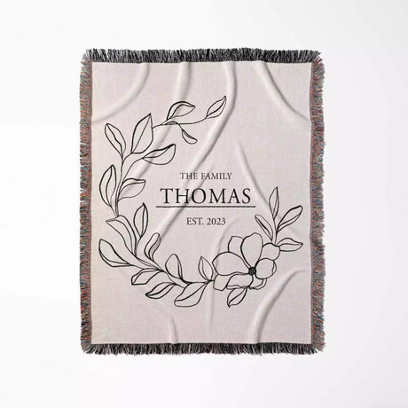 Custom family name cotton throw blanket with floral design and text flat lay on a white background