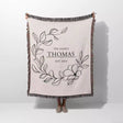 Custom family name cotton throw blanket with floral design and text 'The Family Thomas Est. 2023' on a white background