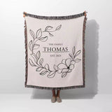 Custom family name cotton throw blanket with floral design and text 'The Family Thomas Est. 2023' on a white background