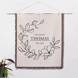 Custom family name cotton throw blanket as a decorative wall hanging with floral design and text on a white background