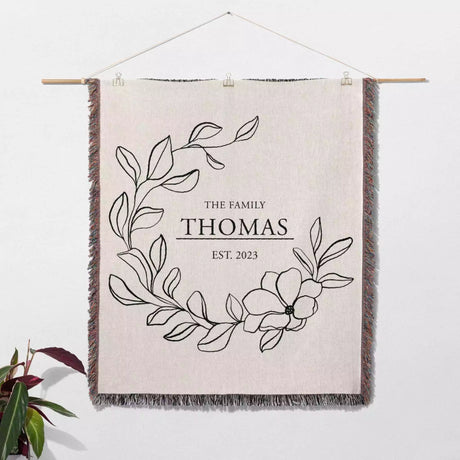 Custom family name cotton throw blanket as a decorative wall hanging with floral design and text on a white background