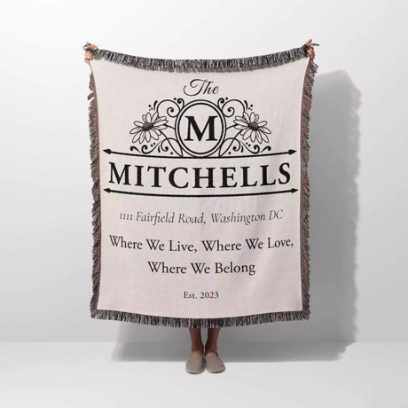 Custom family name and address blanket with 'The Mitchells' design and text held by a person on a white background