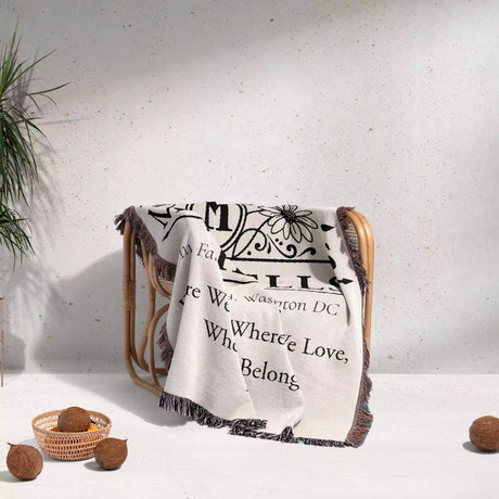 Custom family name and address blanket with text draped over a chair on a light background