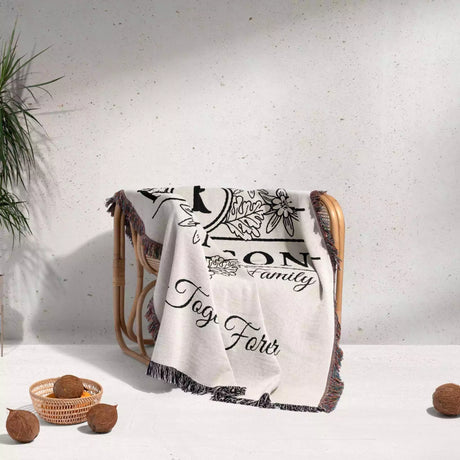 Custom last name cotton blanket with text and graphics draped over a chair on a light background