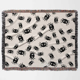 A flat, horizontal layout of the Cute Halloween Blanket with Spiders, showcasing its overall design. The blanket displays an adorable, scattered spider pattern in black on an off-white background. The multicolored fringe runs along the edges, adding a vibrant contrast to the soft tones of the blanket.