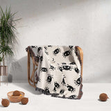 The Cute Halloween Blanket is elegantly draped over a wooden chair, illustrating its cozy and decorative appeal in a kid's room setting. The soft off-white fabric with black spider patterns creates a fun, spooky vibe, perfect for Halloween or everyday use in a playful, themed room.