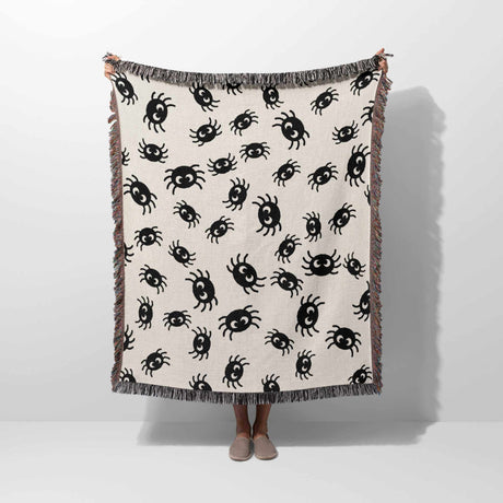 Cute spiders woven throw blanket for halloween décor held by a person on a white background.