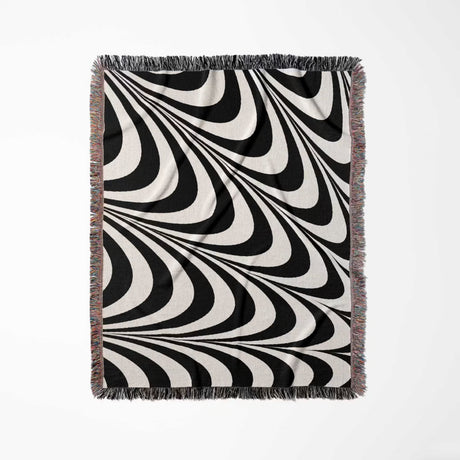 Black and white decorative abstract waves woven blanket throw tapestry full view on a light gray background.
