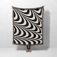 Black and white decorative abstract waves woven blanket throw tapestry draped over a person on a white background.