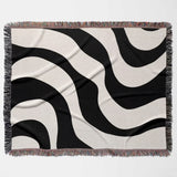 Black and white decorative modern woven blanket throw tapestry flat lay on a beige background