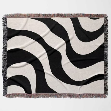 Black and white decorative modern woven blanket throw tapestry flat lay on a beige background