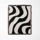 Black and white decorative modern woven blanket throw tapestry with fringe full view on a light gray background