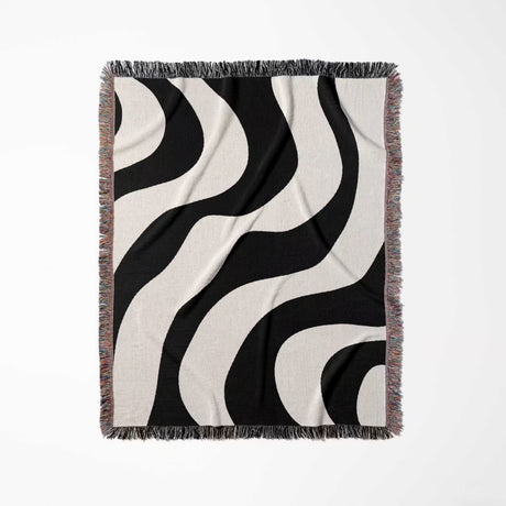 Black and white decorative modern woven blanket throw tapestry with fringe full view on a light gray background