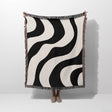 Black and white decorative modern woven blanket throw tapestry held by a person on a white background