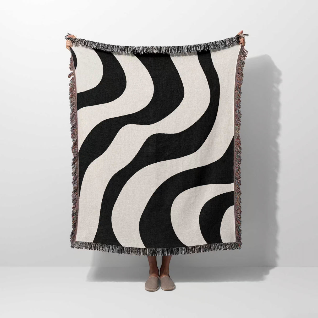 Black and white decorative modern woven blanket throw tapestry held by a person on a white background