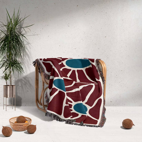 Decorative eclectic Matisse inspired tapestry throw blanket for couch draped over a chair against a white wall.