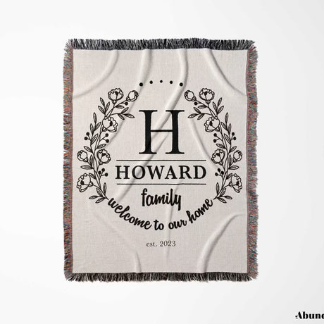 Family monogrammed woven throw blanket for couch and bed with decorative text and floral wreaths full view on a light background