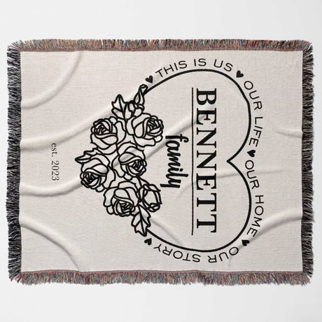 Family name personalized woven throw blanket gift for spouse with floral design and text flat lay on a white background