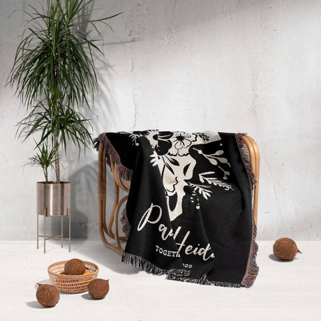 Floral cow skull 2nd anniversary gift woven throw blanket with white floral design and text draped over a chair against a light gray wall.
