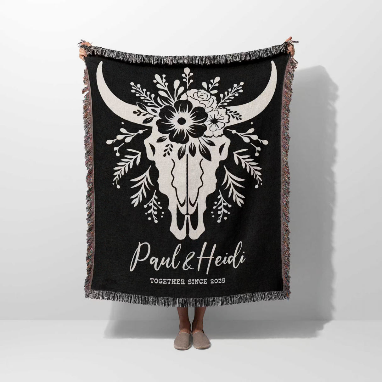 Floral cow skull 2nd anniversary gift woven throw blanket with white bull skull design and custom text held by a person on a white background