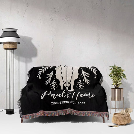 Floral cow skull 2nd anniversary gift woven throw blanket with custom text and designs on a couch in a room with a lamp and plant.