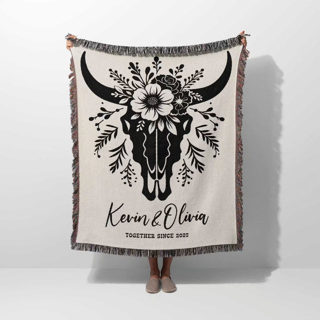 Floral cow skull cotton anniversary gift woven throw blanket held by a person with bull skull design and personalized text on a white background