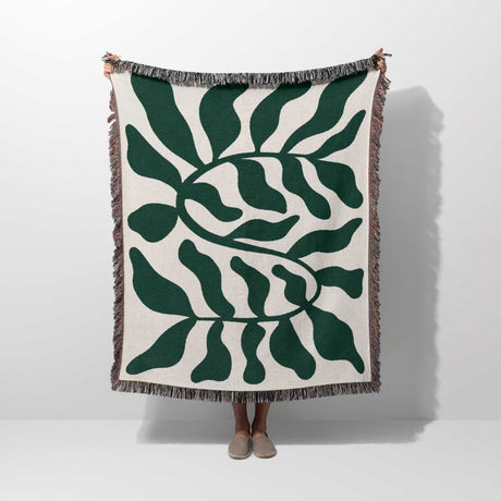 Forest green leaf Matisse throw blanket held by a person on a white background
